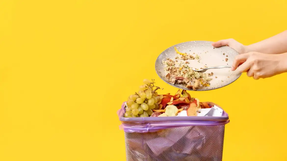 Desperdicio alimentario en España - Cubo de basura con alimentos mientras se desecha plato sin terminar de comer